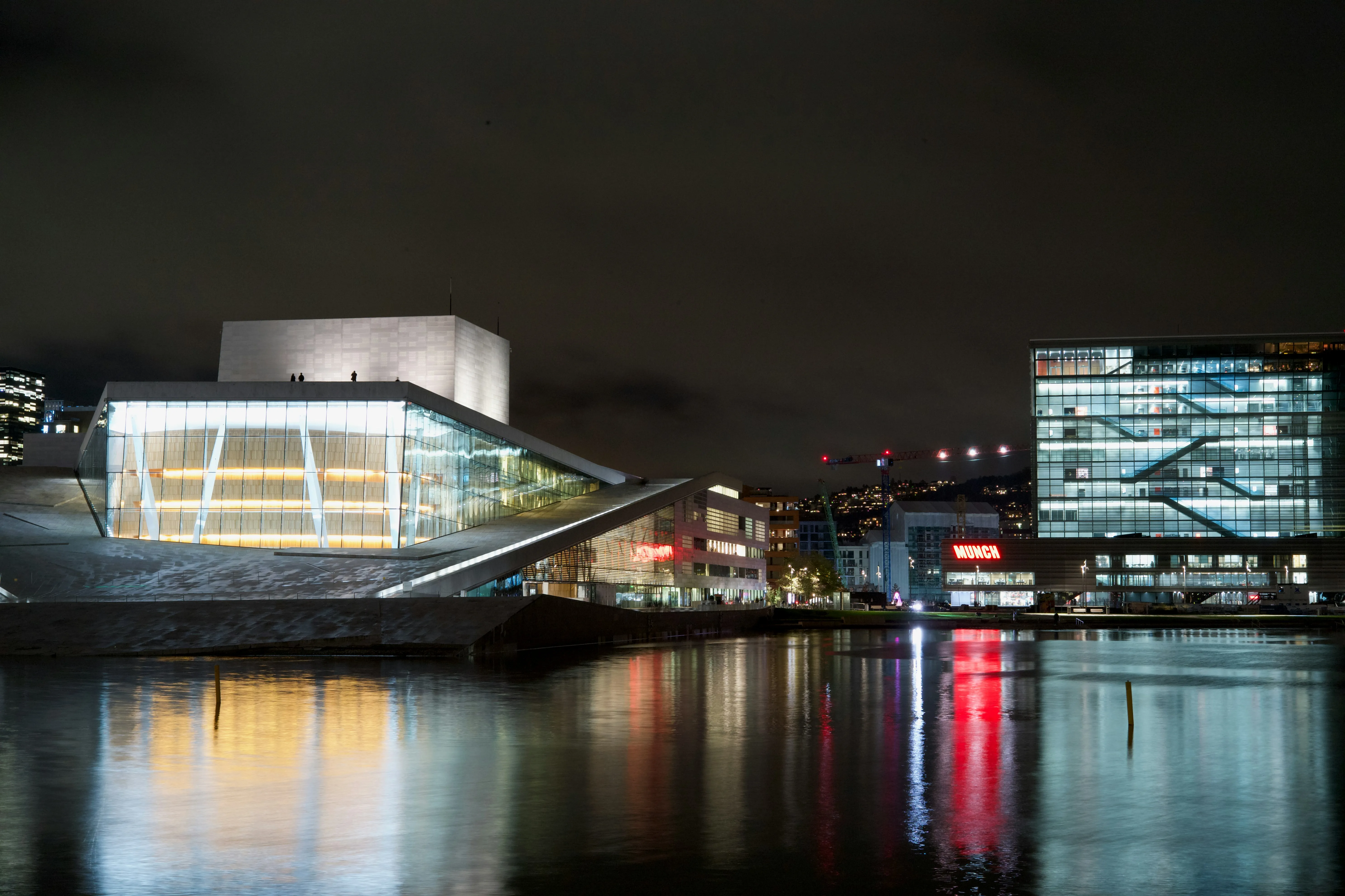 Operaen i Oslo og havnen om natten, lys som speiler seg i fjorden